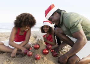 Where it All Began - Blog - Five Family-Friendly Festive Season Favourites in South Africa - Family on the Beach Wearing Christmas Hats and Building a Sandcastle
