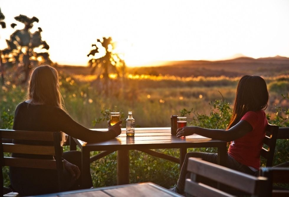 Where It All Began - North Namibian Road Trip Adventure - Damaraland - Palmwag Lodge - Women Drinking Watching Sunset