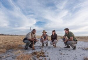 Where It All Began - North Namibian Road Trip Adventure - Etosha National Park - Onguma Tamboti Campsite - Crouching Safari Goers and Guide