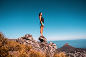 Where It All Began - Blog - Hike it like it’s Hot: 9 Essential Tips for Hiking in Cape Town! - Woman Standing on Mountain Edge Rock