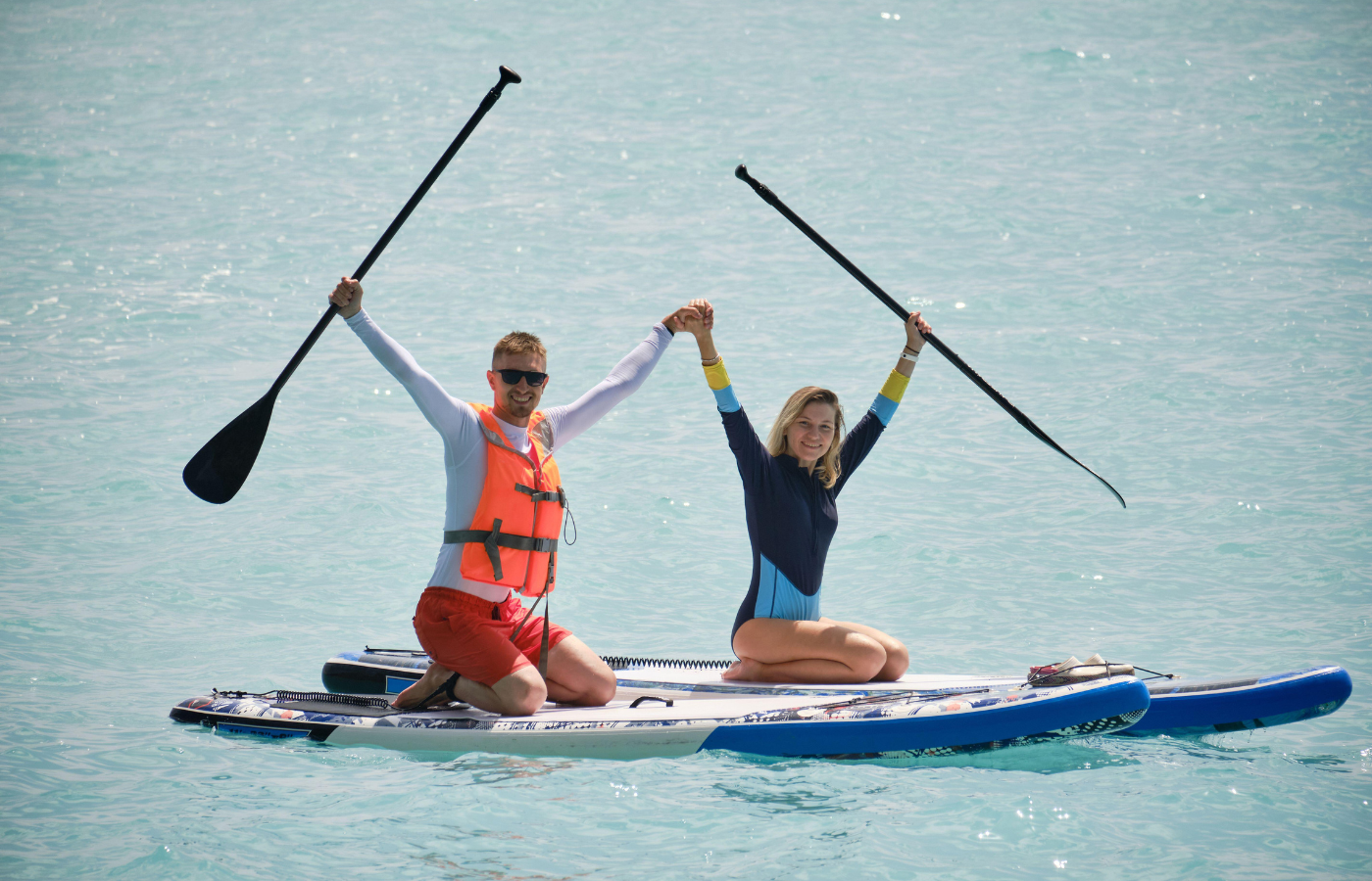 Where It All Began - Journeys - Kitesurfing & Houseboat Escape on the West Coast - Couple on SUP Adventure Holding Hands